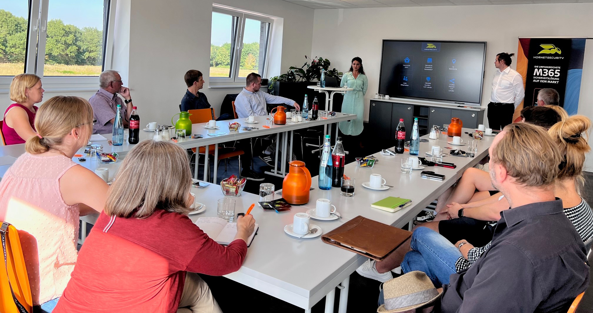 Ein Dutzend Personen in einem Konferenzraum hören einer Präsentation über IT-Sicherheit aufmerksam zu.