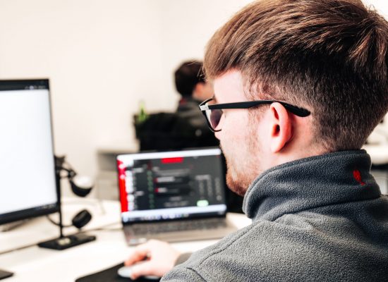P1182527 Ein Mann mit Brille arbeitet konzentriert an einem Computer in einem modernen Büro.
