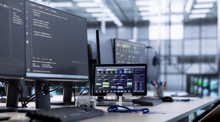 Computers and tablet in empty high tech data center establishment monitoring hardware energy consumption. PC monitors on desk used for checking potential system failures in server room